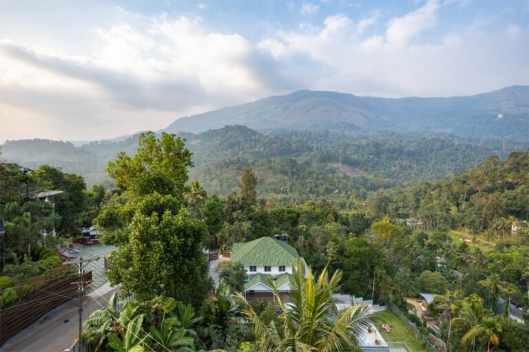 beautiful landscape with mountains in the background, lush greenery, and what seems like a resort or guesthouse with a green roof nestled among the trees. This serene setting could be perfect for promoting a resort or nature-based destination. eco friendly resort lush greenery and breathtaking views Relax and Rejuvenate